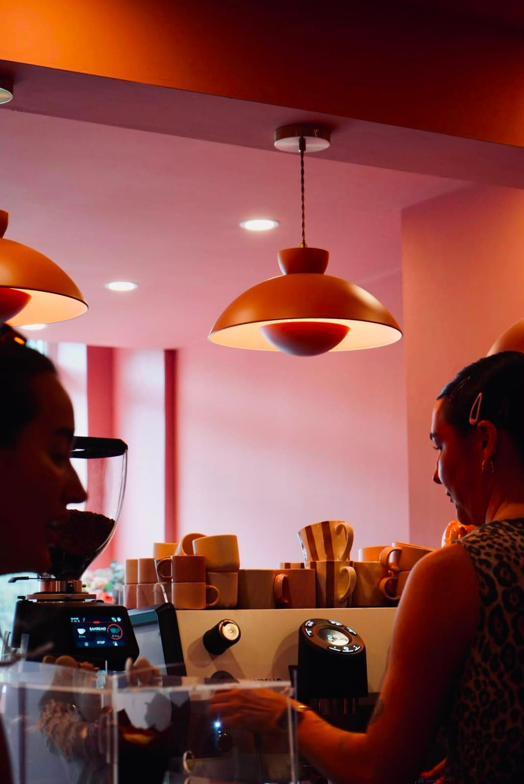 Two baristas working the counter under warm pendant light